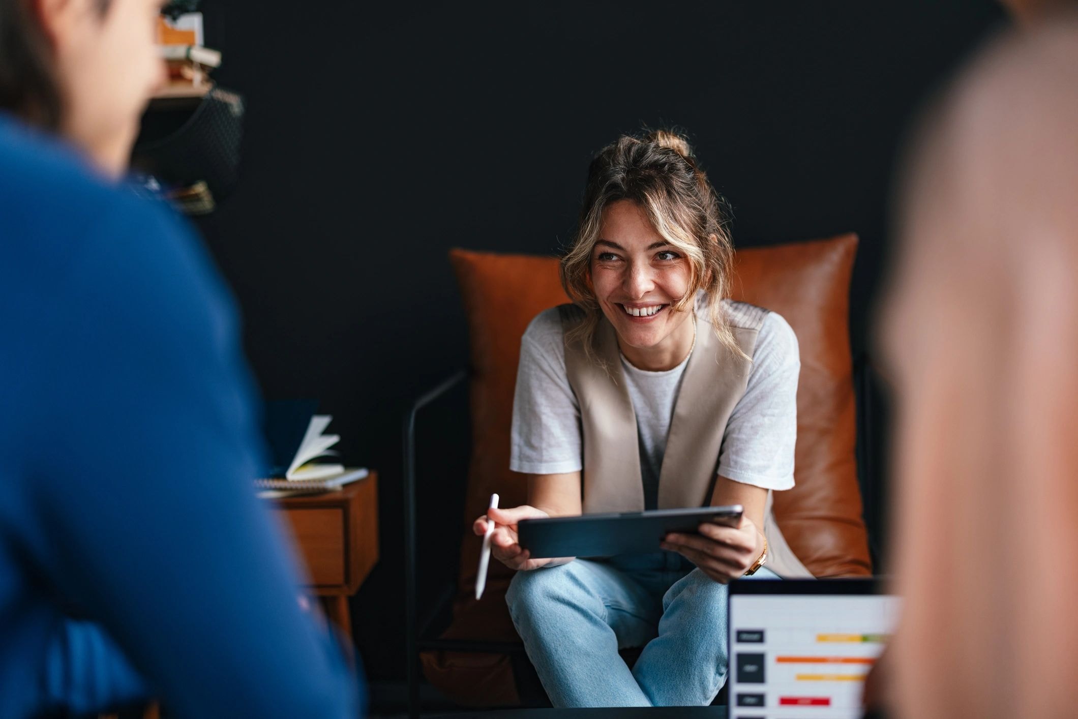 Femme souriante avec tablette lors d'une réunion professionnelle